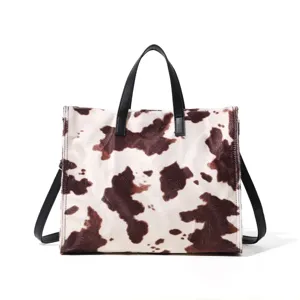 Detailed view of the stylish cow print plush tote bag with black handles and spacious capacity.