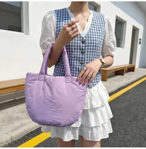 Primo piano dettagliato della borsa tote trapuntata viola chiaro indossata da una modella.