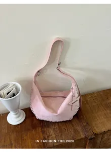 Gedetailleerd overzicht van de retro roze suède schoudertas met studs en sterhanger.
