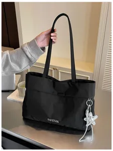Vista dettagliata della borsa tote nera, che evidenzia la texture e il ciondolo a stella.