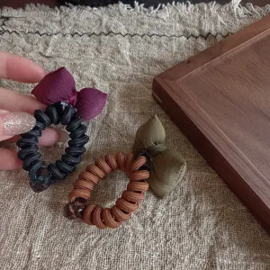 Dettaglio di elastico per capelli a filo telefonico con fiocco imbottito stile coreano per coda.