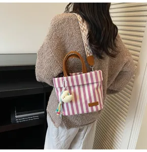 Detail view of the striped canvas crossbody bag showcasing the fabric texture and cute pendant.