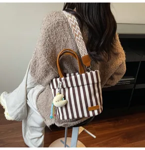 Detailed view of brown white striped canvas tote bag with wide strap and cute charm.