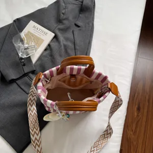 Striped canvas tote bag with brown leather handles and casual crossbody strap for daily commute.