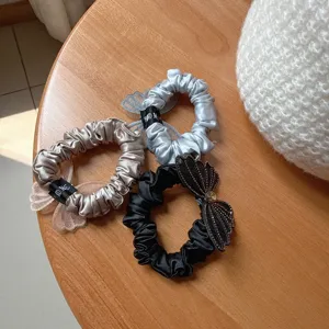 Close-up detail of stylish satin hair scrunchies featuring mesh butterfly and rhinestones.