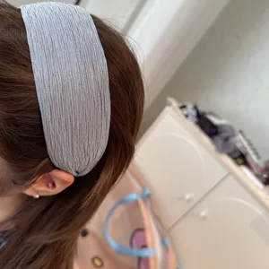 Detail shot of a grey pleated wide fabric headband worn, showing soft texture and comfortable fit.
