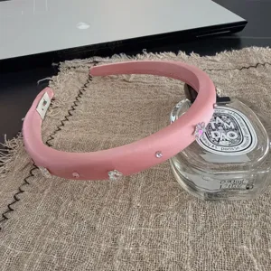 Detail shot of a pink satin headband decorated with sparkling crystal stars and gems on linen.