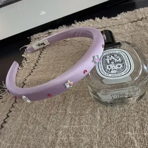 Detailed shot of a lavender satin padded headband decorated with sparkly stars and rhinestones.