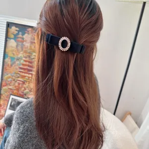 Elegant black velvet bow hair clip with sparkling rhinestone ring, perfect for women styling.