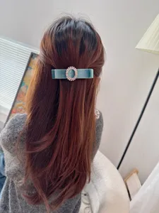 Detail view of the elegant blue velvet hair clip with sparkling oval rhinestone buckle.