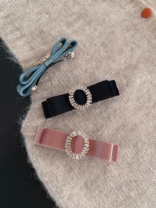 Close-up detail of retro velvet bow hair clips with sparkling rhinestone oval buckle designs.
