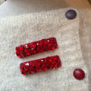 Close-up van rode strass haarklemmen, sprankelende kristaldetails voor zoete dagelijkse looks.