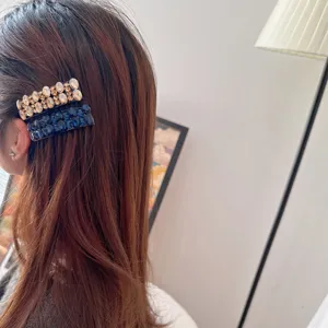 Vue détaillée de pinces à cheveux scintillantes en strass sur des cheveux bruns.