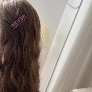 Vue détaillée d'un peigne à cheveux en strass étincelant porté sur des cheveux ondulés.