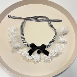 Detail shot of cute pet lace bib collar with black checkered ribbon bow and bell accessory.