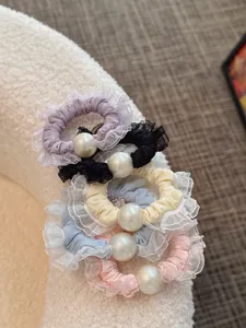Close-up detail shot of elegant mesh lace scrunchies with large pearl charm, soft fabric.