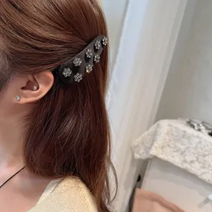 Detailed close-up of a vintage satin rhinestone flower hair clip, elegant side accessory.