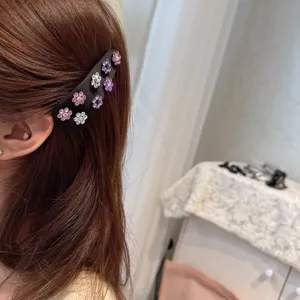 Detailed view of a black satin rhinestone flower hair clip worn on brown hair, elegant accessory.