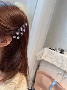 Close-up detail of satin rhinestone flower hair clip worn on side hair, sparkling floral design.