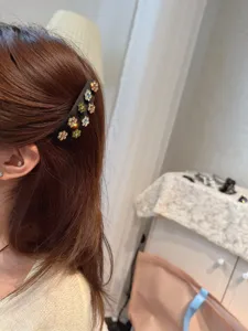 Close-up detail of the retro fabric rhinestone flower BB hair clip worn on side hair.