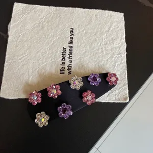 Rhinestone flower hair clip detail shot showing sparkling crystals on black satin fabric.