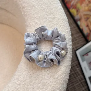 Detailed view of an elegant grey-blue satin hair scrunchie adorned with chic faux pearls.
