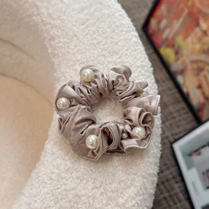 Satin pearl hair scrunchie close-up, elegant shiny fabric ruffle hair tie detail shot.