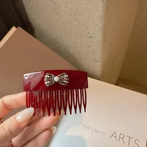 Detailed view of wine red acrylic hair comb featuring a sparkling rhinestone pearl bow ornament.