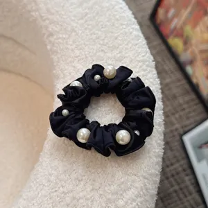 Korean style fabric pleated black scrunchie with elegant white pearls for women hair styling.
