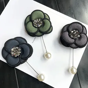 Detail view of elegant fabric camellia flower brooches with sparkling rhinestones and pearls.