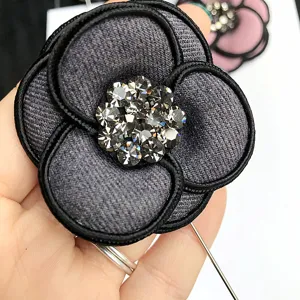 Close up view of the grey fabric camellia brooch with sparkling center rhinestones and pin.