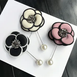 Vintage camellia flower brooch pin with sparkling rhinestones and pearl ends, elegant fashion jewelry.