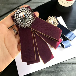 Vintage crystal pearl fabric bow brooch detail shot, elegant burgundy collar pin accessory.