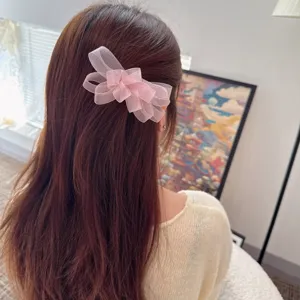 Close-up detail shot of a pink mesh bow hair clip worn elegantly on soft brown hair.