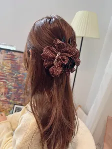 Detailed view of a brown polka dot mesh hair claw clip, elegant accessory for women styling.