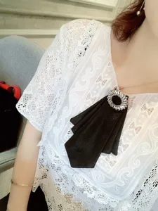 Broche de lazo de tela negra con círculo de pedrería brillante, foto de detalle de accesorio.