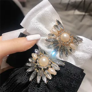 Dettaglio spilla fiocco in strass cristalli, pietre scintillanti e perla, elegante accessorio camicia.
