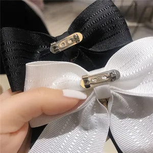 Primo piano dettagliato delle eleganti spille per colletto con fiocco bianco e nero.