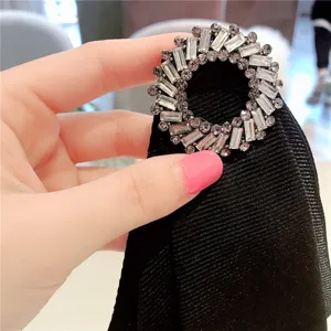 Primer plano detallado de broche de cuello circular con pedrería brillante, accesorio elegante.