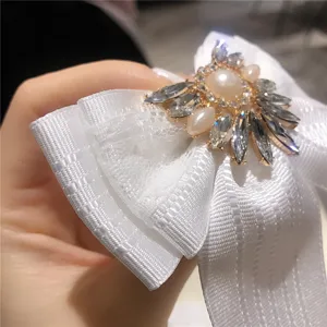 Primo piano dettagliato di una spilla a fiocco bianca con strass scintillanti e perla.
