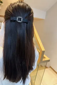 Detailed shot of a black fabric hair bow featuring a sparkling crystal square rhinestone buckle.