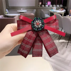Gros plan détaillé d'une élégante broche nœud écossais rouge avec centre de fleurs en strass.