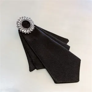 Primer plano detallado de pajarita de tela negra con broche de anillo de diamantes de imitación.