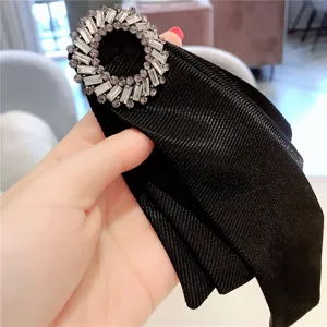 Vista detallada de un broche de lazo negro con una hebilla redonda de pedrería brillante