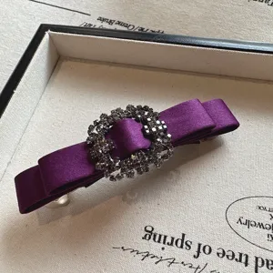 Purple satin bow hair clip detail with sparkling rhinestones, elegant spring clip accessory.