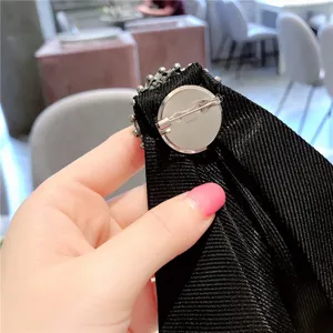 Detalle trasero de broche lazo estrás negro, elegante pin de cuello cristal para mujer.