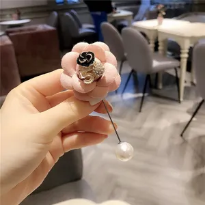 Primo piano dettagliato dell'elegante spilla camelia rosa con numero 5 in strass e spilla perla.