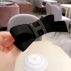 Black fabric bow hair clip with rhinestone H buckle elegant hair accessory for women ponytail.