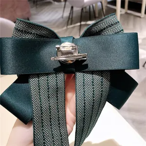 Vue de détail en gros plan du nœud papillon vert foncé à motif chevron avec pince métallique.