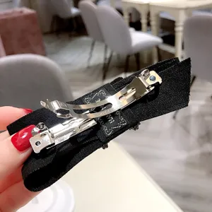 Black bow hair clip detail view, elegant fabric hair barrette with sparkling rhinestones for women.